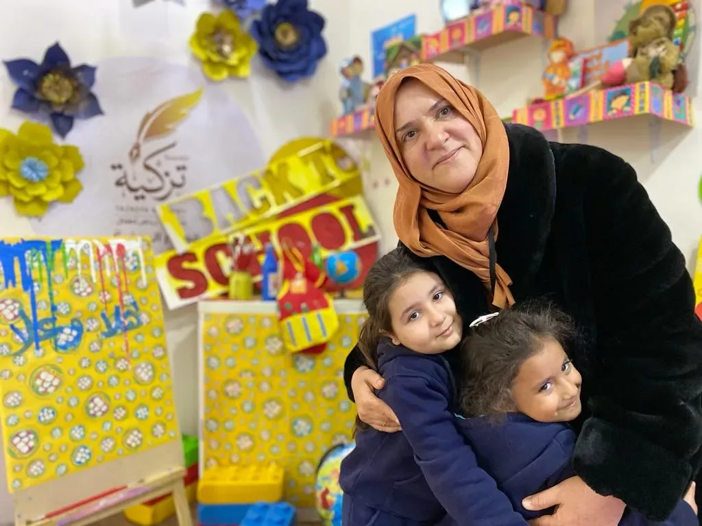 معلمة مع طفلين في مساحة تعليمية في أكاديمية تزكية الدولية